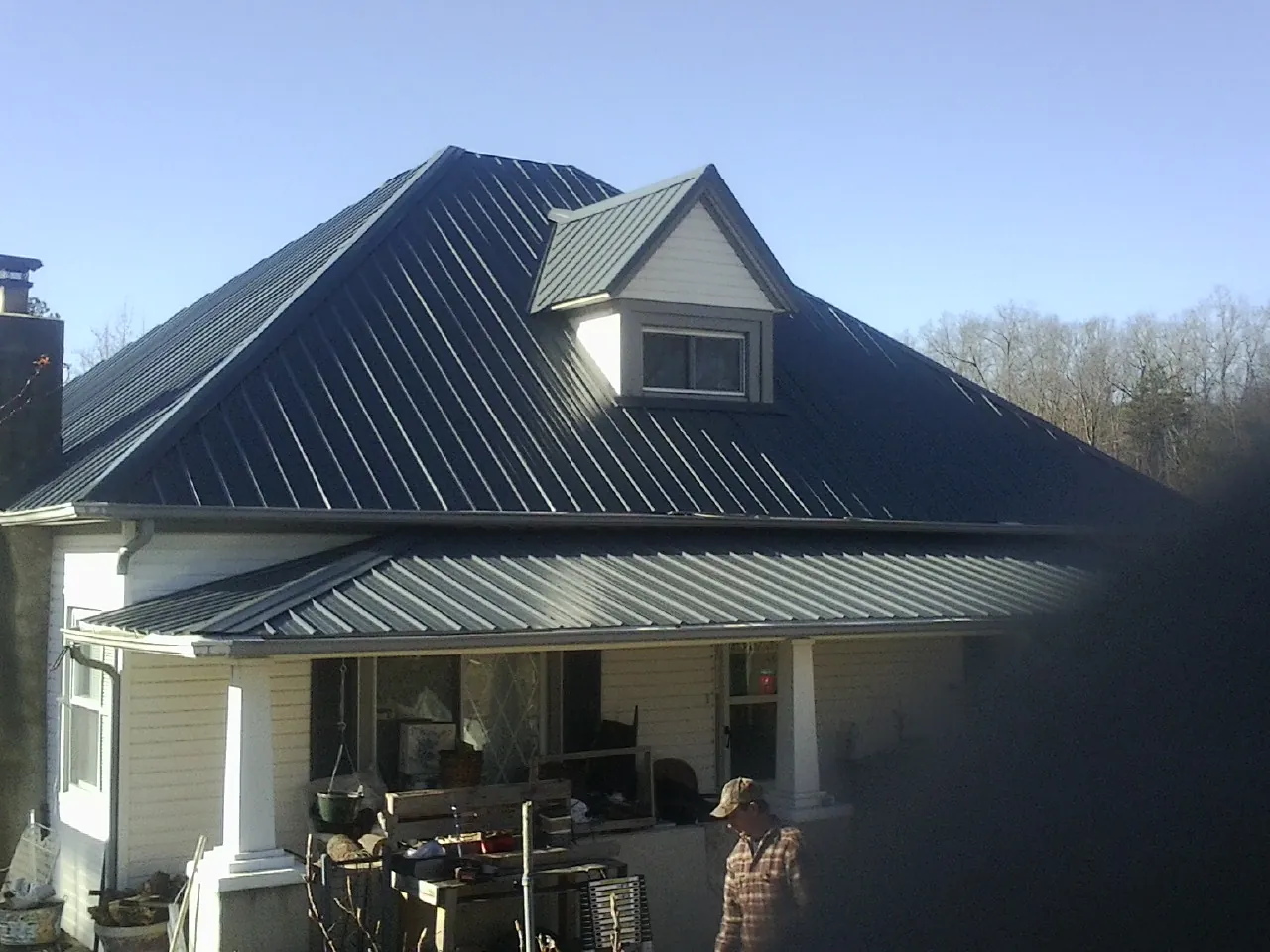 Dark blue standing seam metal roof with a dormer above a front porch in East Grand Forks