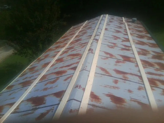Rusted metal roof panels with new wood purlins before replacement — Storm Damage Roof Repair in East Grand Forks by Roofing Brothers
