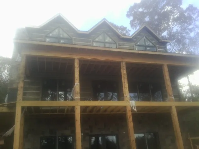 Dormers and porch framing on a large log home under construction — Roof Coating work by our crew in East Grand Forks