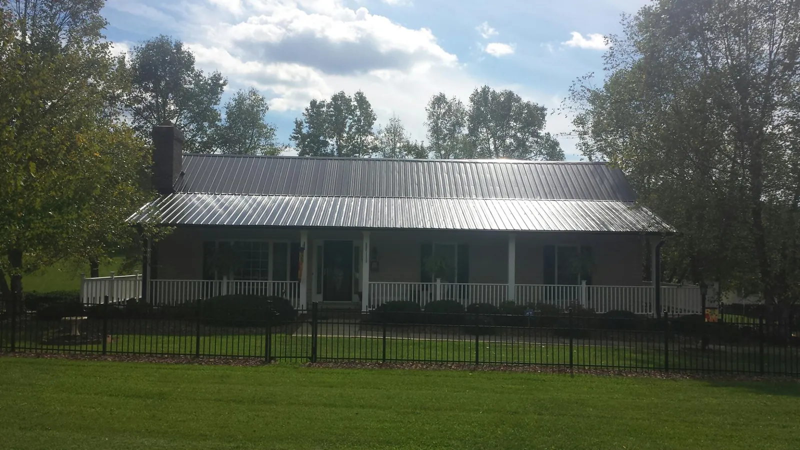 Gray metal roof on a brick ranch with a full width front porch — Gutter Guard Installation work by our crew in East Grand Forks