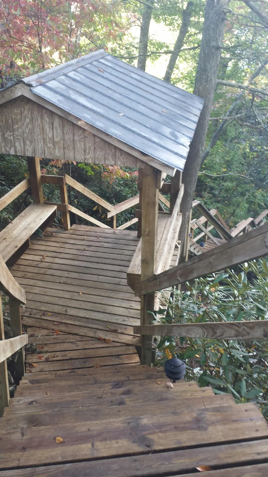 Metal roofed shelter over wooden steps on a wooded walkway — Skylight Repair & Installation work by our crew in East Grand Forks