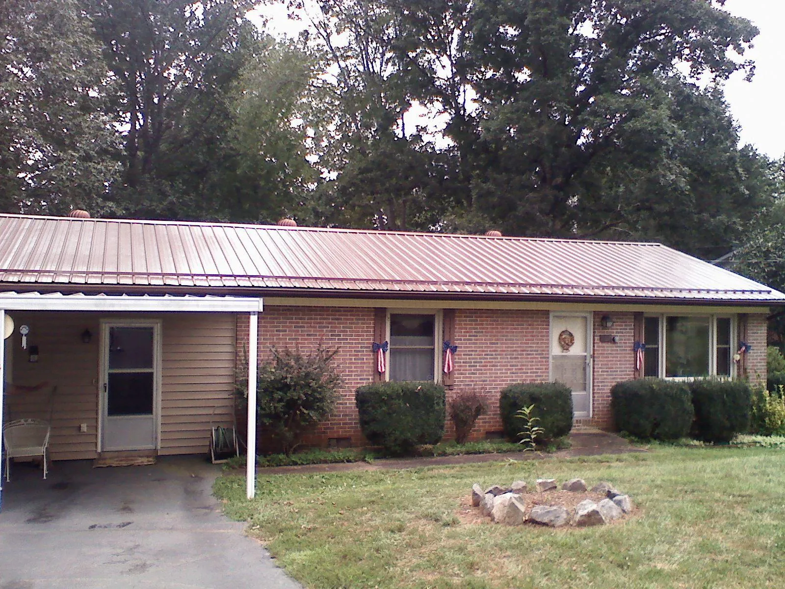 Bronze metal roof and carport on a brick ranch home — Roof Repair work by our crew in East Grand Forks