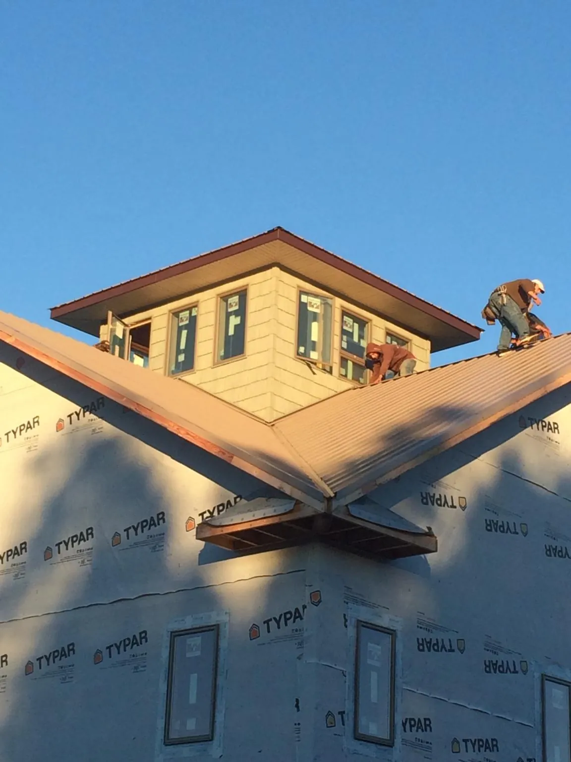 Roofers working around a rooftop cupola on a new metal roof at sunset — Roof Waterproofing in East Grand Forks by Roofing Brothers